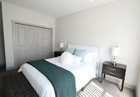A bedroom with a large bed and a small bedside table.