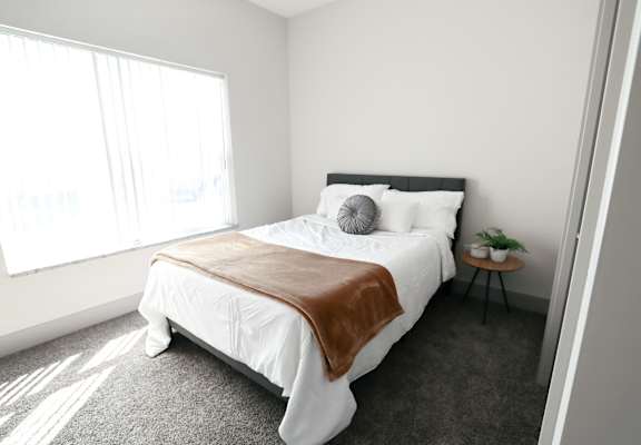A bedroom with a large bed and a small table with a plant on it.