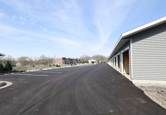 A long, empty road stretches out in front of a building with a grey exterior.