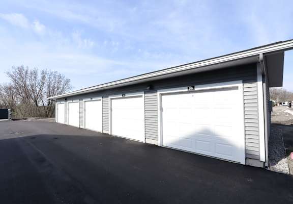 A long garage with a white door is on a sunny day.