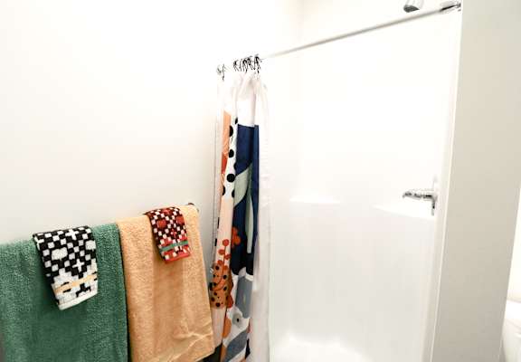 A white door is behind a towel rack with four towels hanging on it.