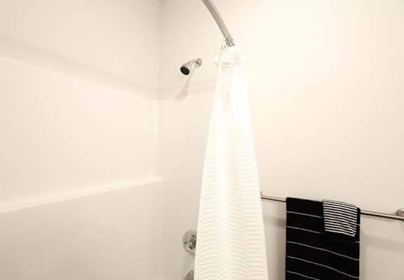 A white shower curtain hanging from a rod in a bathroom.