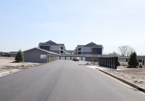 A large grey building with a long driveway in front of it.