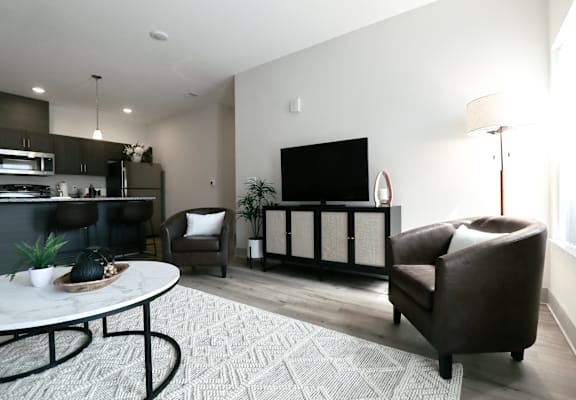 A modern living room with a white coffee table and brown leather couch.