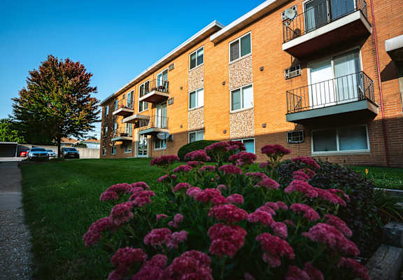a brick apartment building with balconies and pink flowers