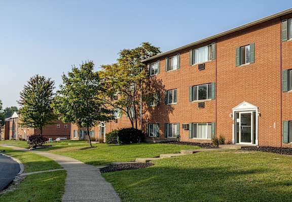 a brick apartment building with a sidewalk in front of it
