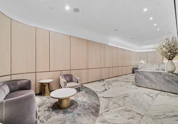 A modern living room with a grey sofa, a round gold coffee table, and a marble countertop. at Aria, New York