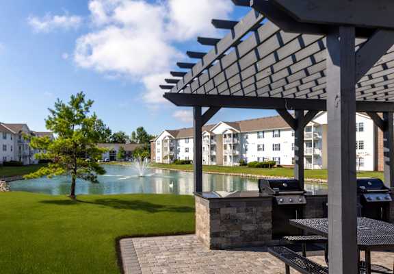 A patio with a table and chairs overlooking a pool.