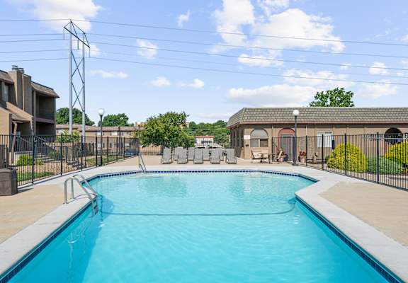 A large swimming pool surrounded by a fence and a building in the background.