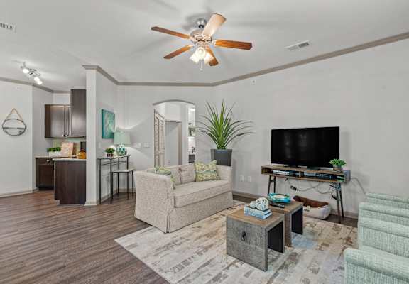 A living room with a beige couch, a wooden coffee table, and a television on a stand.