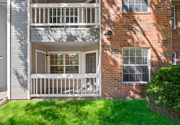 A balcony with a white railing and a window with blinds.