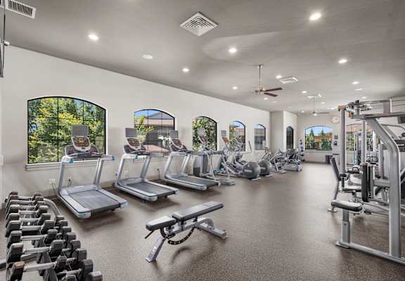 A spacious gym with treadmills, elliptical machines, and dumbbells.
