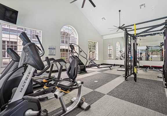 A gym with a variety of equipment including a stationary bike and a pull up bar.