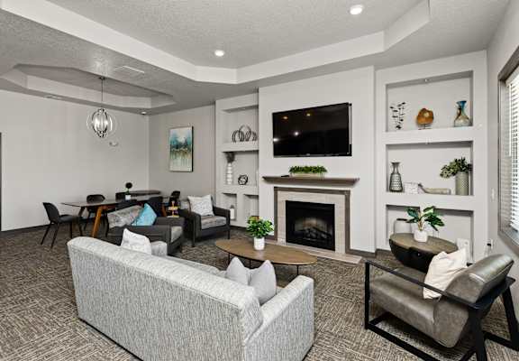 A living room with a grey couch and a fireplace.