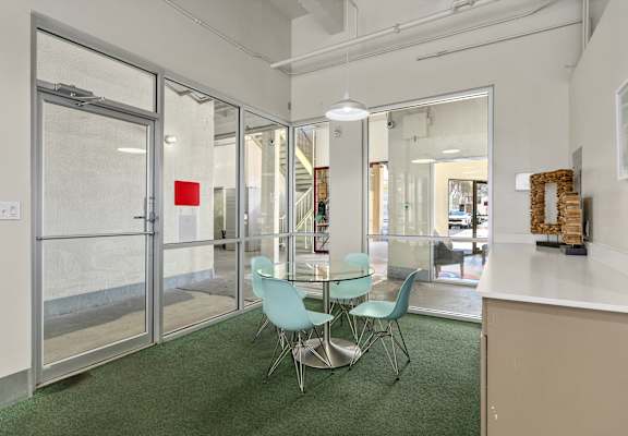 A glass door with a red sign on it is in a room with a table and chairs.
