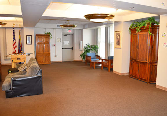 A room with a black couch and a wooden cabinet.