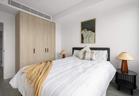 A bedroom with a bed, a lamp, and a painting on the wall.