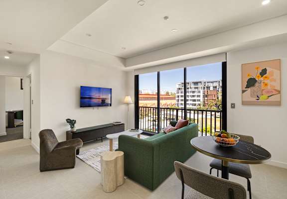 A living room with a green couch, a brown chair, a coffee table, and a painting on the wall.