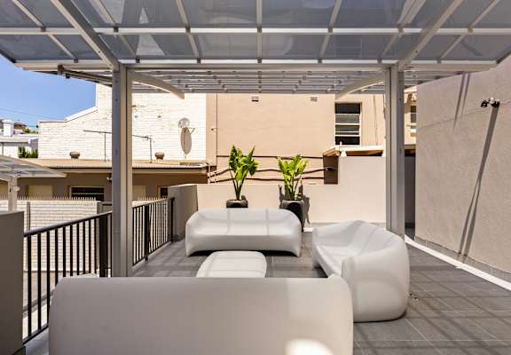 A white patio with a couch and a table.