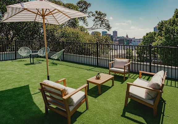 a rooftop terrace with lawn chairs and an umbrella