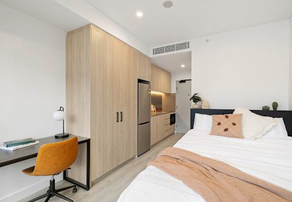 A bedroom with a bed, desk, and chair.