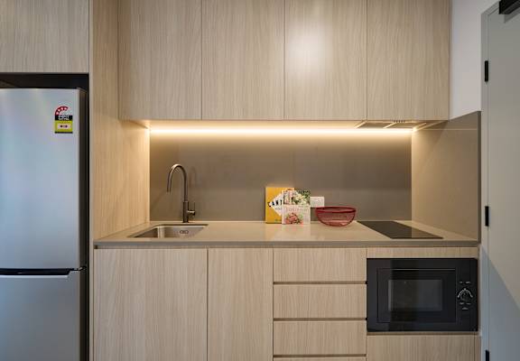 A modern kitchen with a refrigerator, sink, and microwave.