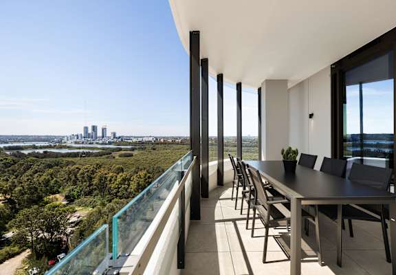 A modern balcony with a table and chairs overlooking a city skyline.