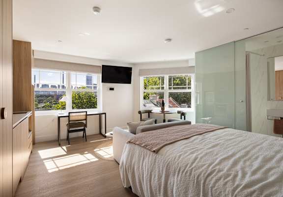A bedroom with a large bed and a desk with a chair.