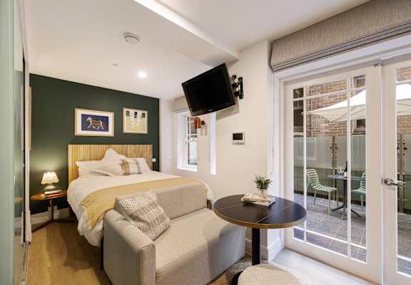 A bedroom with a bed, a couch, a table, and a television.