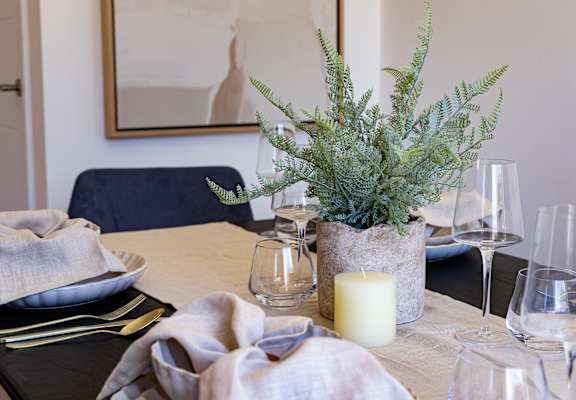 A dining table set with a candle and a potted plant.