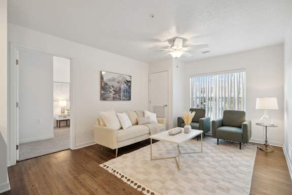 A living room with a white couch, a coffee table, and a painting on the wall.