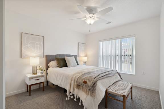 A bedroom with a bed, a bench, and two lamps.
