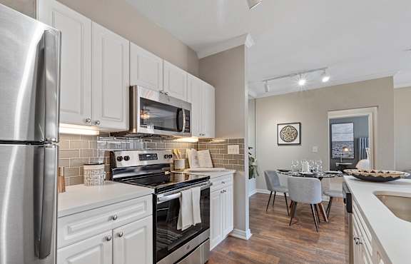 A modern kitchen with white cabinets and stainless steel appliances.