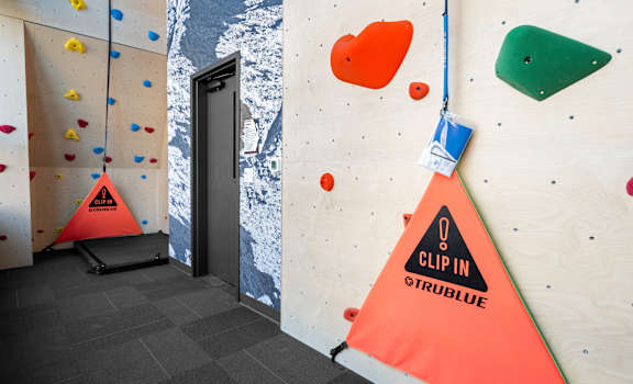 a climbing wall with an orange triangular sign and a door