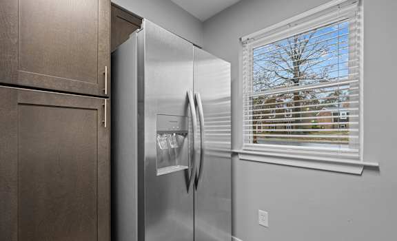 A stainless steel refrigerator in a kitchen with brown cabinets.
