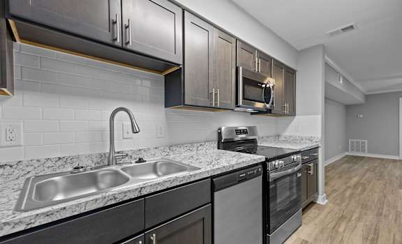 A modern kitchen with a sink, stove, and microwave.