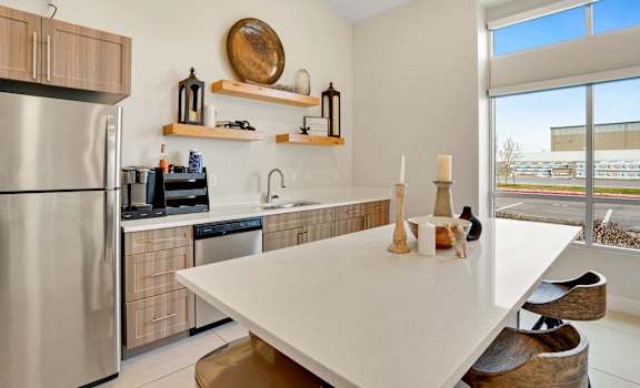 a kitchen with stainless steel appliances and a white table at Altair at Riverwalk Apartments available for rent in West Haven, Utah.