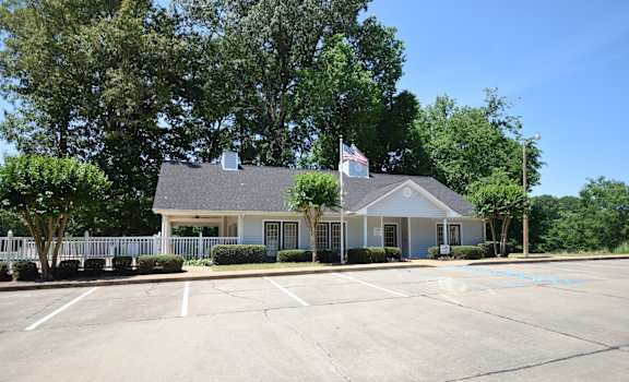 A building with a flag on top and a parking lot in front.