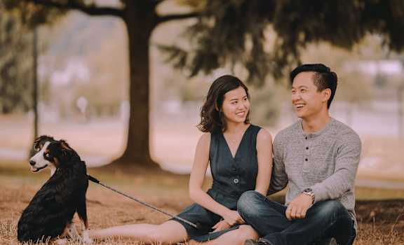 a couple sitting in the grass with their dog