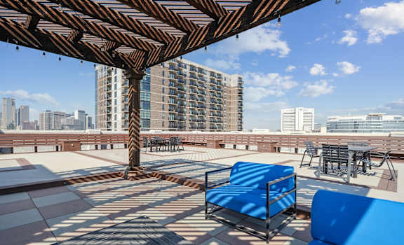 a rooftop patio with blue furniture and a city skyline in the background