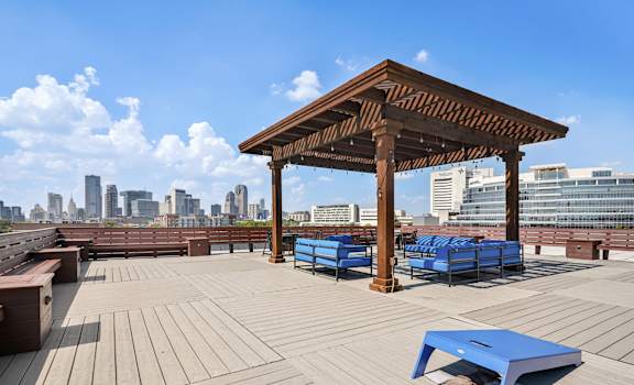 a rooftop deck with benches and a wooden pavilion with a city in the background