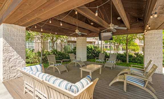 A wooden patio with a couch and chairs.