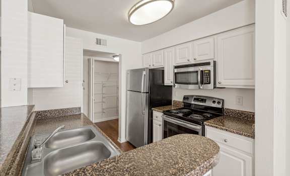 a kitchen with granite countertops and white cabinets at Stonebriar Woods Apartments, Overland Park, KS