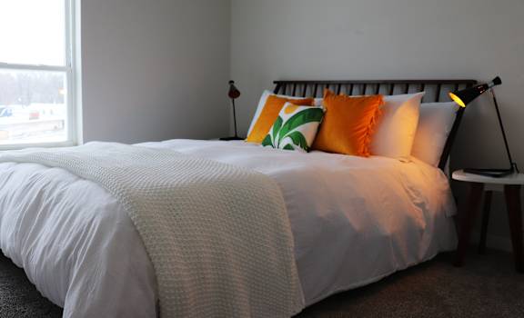 a bed with orange and green pillows and a white comforter