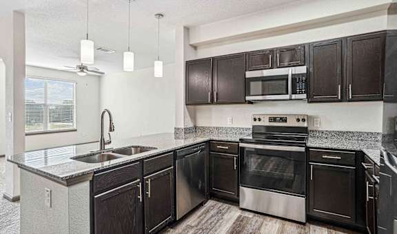 A kitchen with black cabinets and stainless steel appliances.