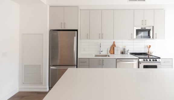 a kitchen with a long island and three stools in front of a white counter