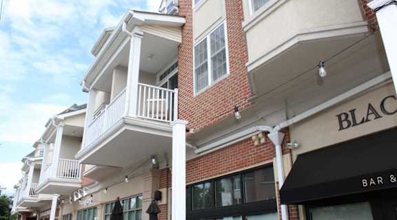 the facade of a brick building with a balcony and a black bar