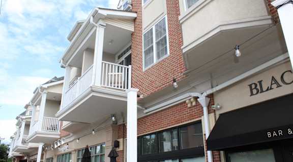 the facade of a brick building with a balcony and a black bar