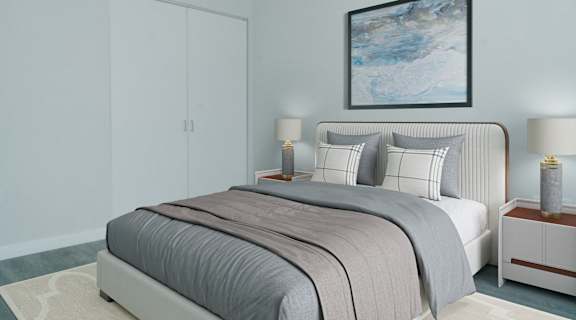 A bed with a grey comforter and pillows is in the image.