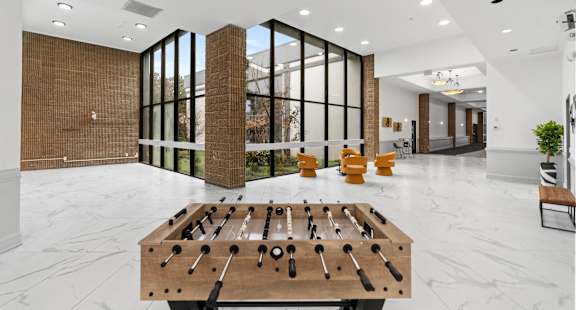 A foosball table sits in the middle of a white marble floor.